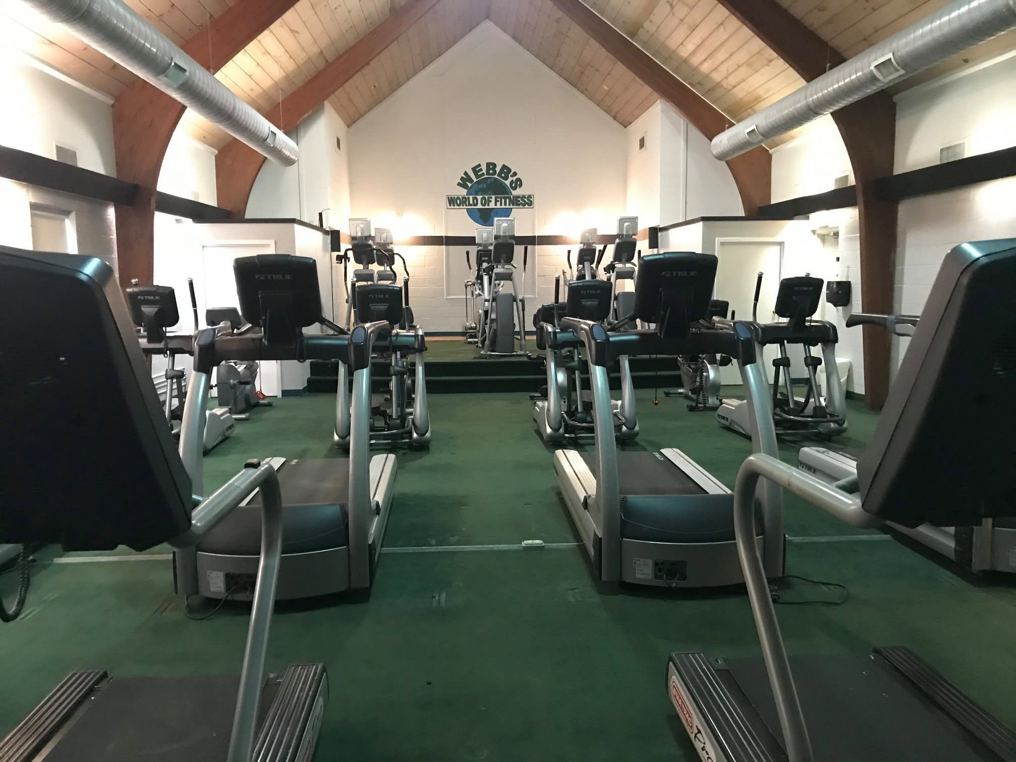 The cardio theater — treadmills and ellipticals under the Webb's World of Fitness sign